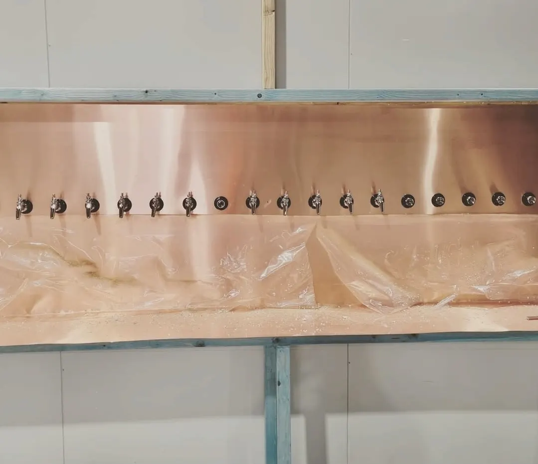 A copper tap wall fitted with beer taps during a bar fit-out.